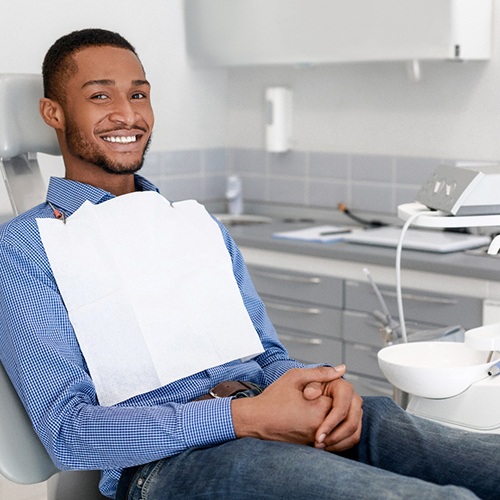 Male dental patient sitting in chair with hands folded