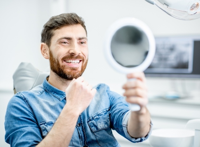 Dental patient seeing his new smile in a mirror