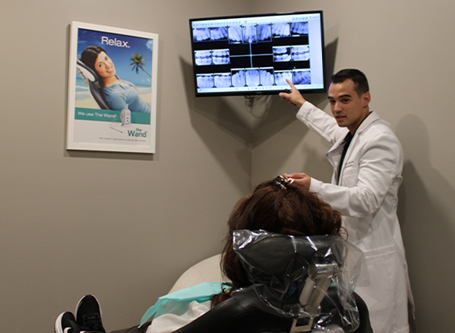 Doctor Perez pointing to dental x rays while explaining dental services in Marco Island to patient