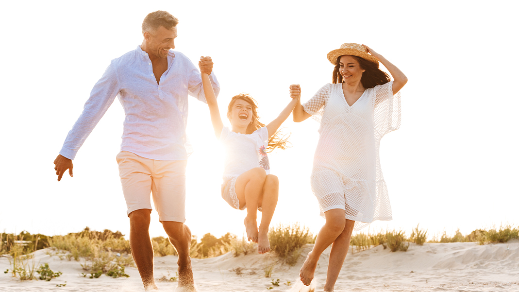 Family of three laughing on the beach