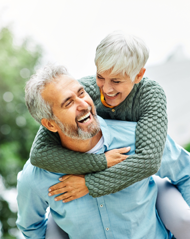 Laughing senior couple holding each other outdoors